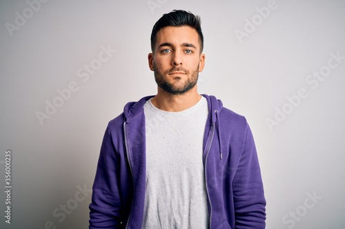 Foto Young handsome man wearing purple sweatshirt standing over isolated white background with serious expression on face