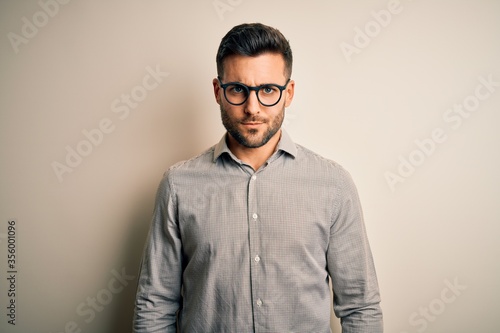 Young handsome man wearing elegant shirt and glasses over isolated white background skeptic and nervous, frowning upset because of problem. Negative person. © Krakenimages.com