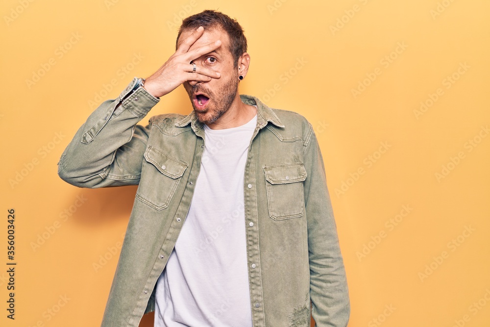 Young handsome man wearing casual clothes peeking in shock covering face and eyes with hand, looking through fingers with embarrassed expression. Young handsome man wearing casual clothes peeking in shock covering face and eyes with hand, looking through fingers with embarrassed expression.