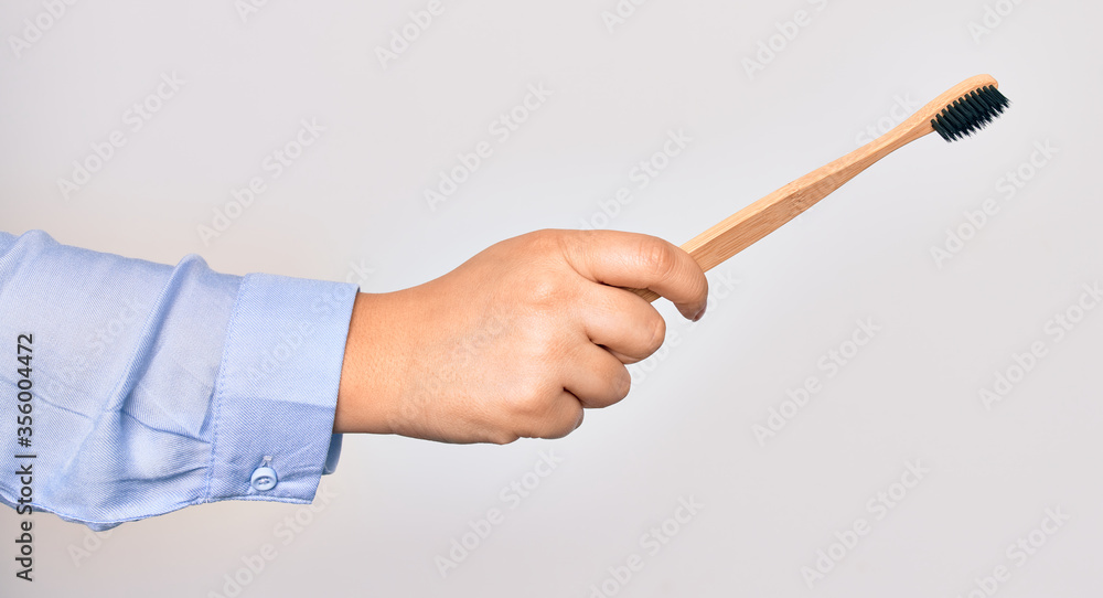 Hand of caucasian young woman holding toothbrush over isolated white background Hand of caucasian young woman holding toothbrush over isolated white background