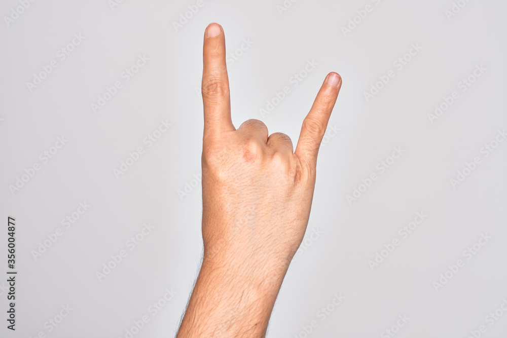 Hand of caucasian young man showing fingers over isolated white background gesturing rock and roll symbol, showing obscene horns gesture Hand of caucasian young man showing fingers over isolated white background gesturing rock and roll symbol, showing obscene horns gesture