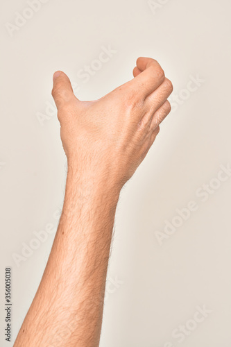 Hand of caucasian young man showing fingers over isolated white background holding invisible object, empty hand doing clipping and grabbing gesture