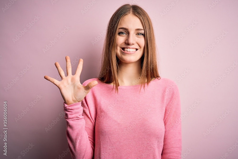 Young beautiful redhead woman wearing casual sweater over isolated pink background showing and pointing up with fingers number five while smiling confident and happy. Young beautiful redhead woman wearing casual sweater over isolated pink background showing and pointing up with fingers number five while smiling confident and happy.
