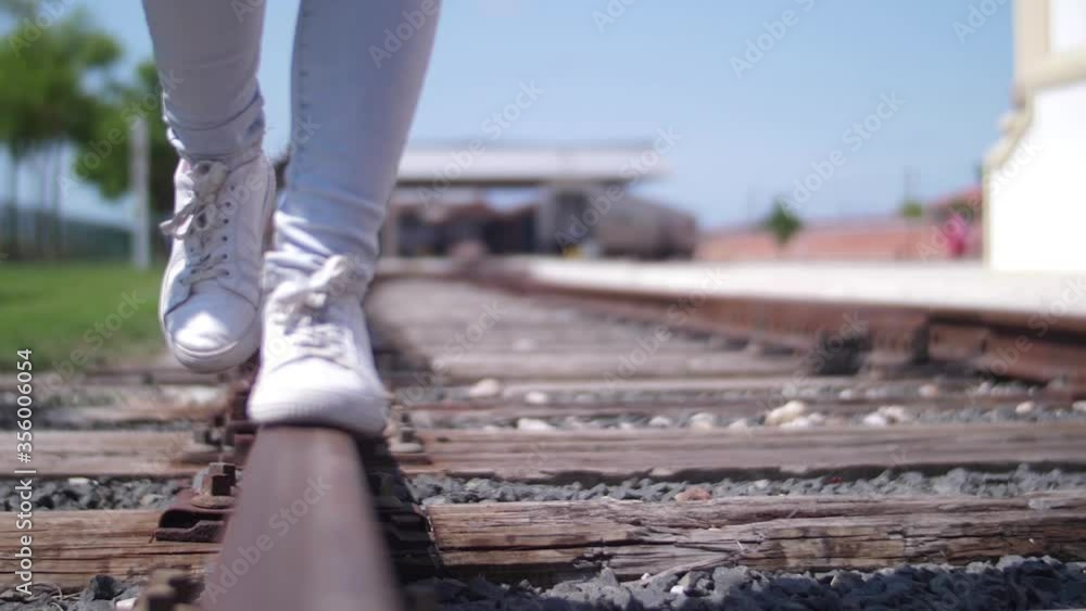 young woman walking in balance on railway tracks slow motion
