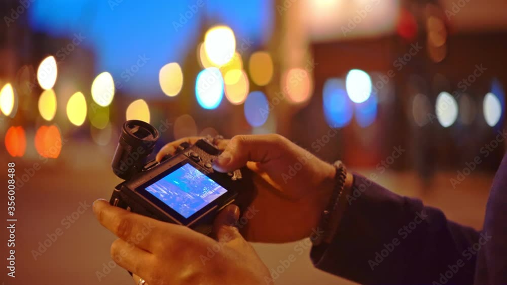 Close up of a man scrolling through the settings of his camera at night Close up of a man scrolling through the settings of his camera at night