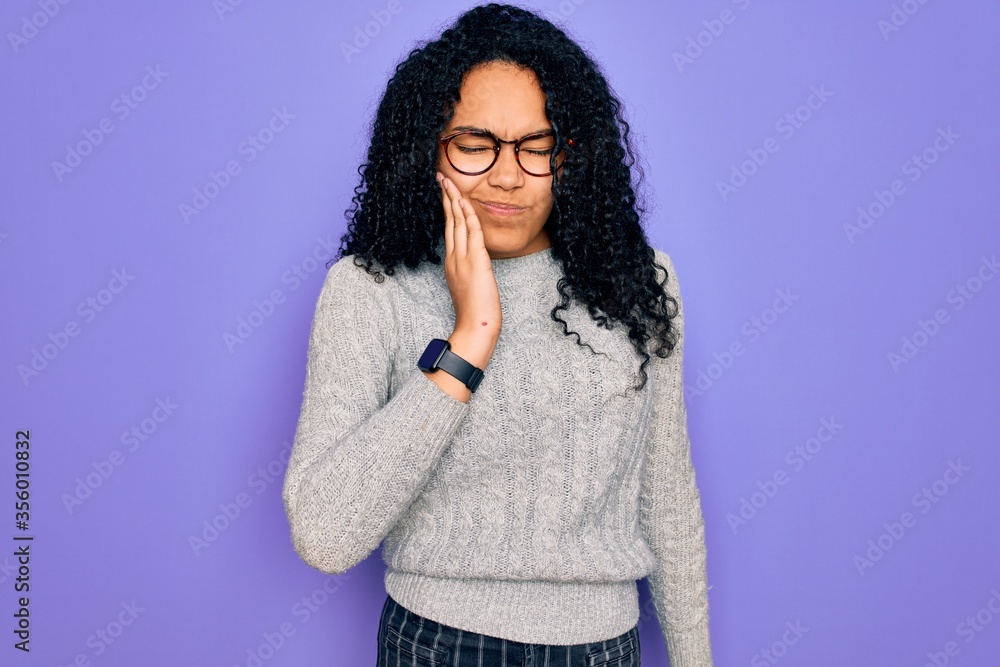 Young african american woman wearing casual sweater and glasses over purple background touching mouth with hand with painful expression because of toothache or dental illness on teeth. Dentist Young african american woman wearing casual sweater and glasses over purple background touching mouth with hand with painful expression because of toothache or dental illness on teeth. Dentist