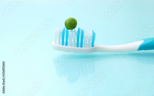 Foto A tooth brush on a hygienic background, with a green pea on it