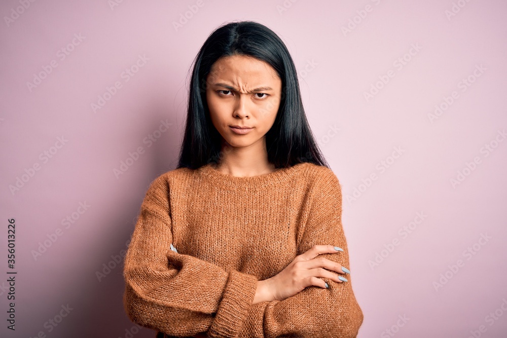 Fototapeta premium Young beautiful chinese woman wearing casual sweater over isolated pink background skeptic and nervous, disapproving expression on face with crossed arms. Negative person.