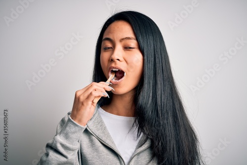 Young beautiful woman smiling happy. Standing with smile on face whasing tooth using toothbrush over isolated white background