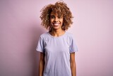 Young beautiful african american woman wearing casual t-shirt standing over pink background with a happy and cool smile on face. Lucky person.