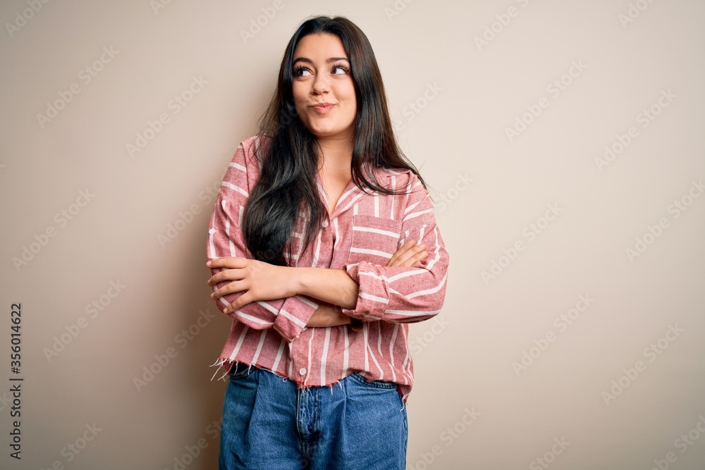 Young brunette woman wearing casual striped shirt over isolated background smiling looking to the side and staring away thinking. Young brunette woman wearing casual striped shirt over isolated background smiling looking to the side and staring away thinking.