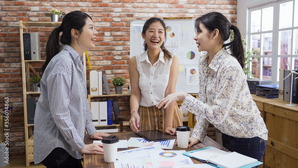Business colleagues laughing during meeting. elegant asian chinese lady coworkers standing at table and cheerful smiling together. girl employee sharing ideas in boardroom in modern office. Business colleagues laughing during meeting. elegant asian chinese lady coworkers standing at table and cheerful smiling together. girl employee sharing ideas in boardroom in modern office.