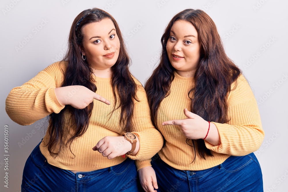 Young plus size twins wearing casual clothes in hurry pointing to watch time, impatience, upset and angry for deadline delay Young plus size twins wearing casual clothes in hurry pointing to watch time, impatience, upset and angry for deadline delay