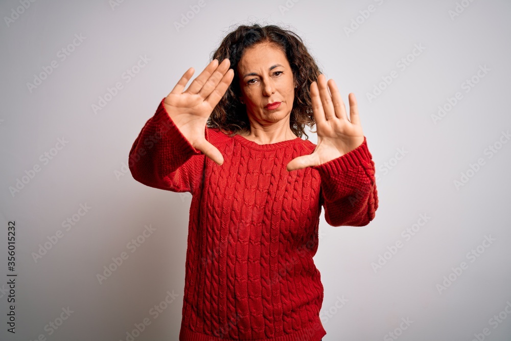 Middle age brunette woman wearing casual sweater standing over isolated white background doing frame using hands palms and fingers, camera perspective Middle age brunette woman wearing casual sweater standing over isolated white background doing frame using hands palms and fingers, camera perspective