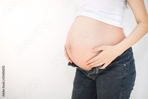 Pregnant woman trying to wear her jeans closeup © Thodsapon