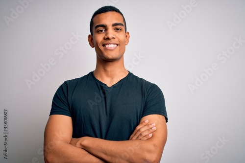 Foto Young handsome african american man wearing casual t-shirt standing over white background happy face smiling with crossed arms looking at the camera