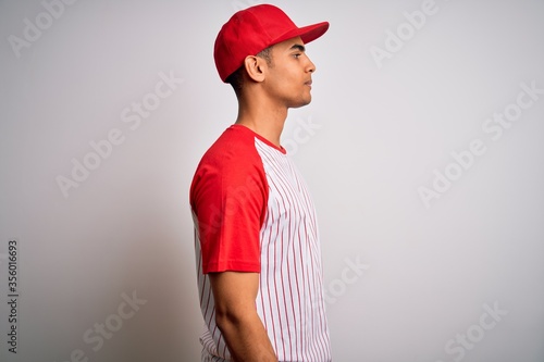 Canvas Print Young handsome african american sportsman wearing striped baseball t-shirt and cap looking to side, relax profile pose with natural face and confident smile