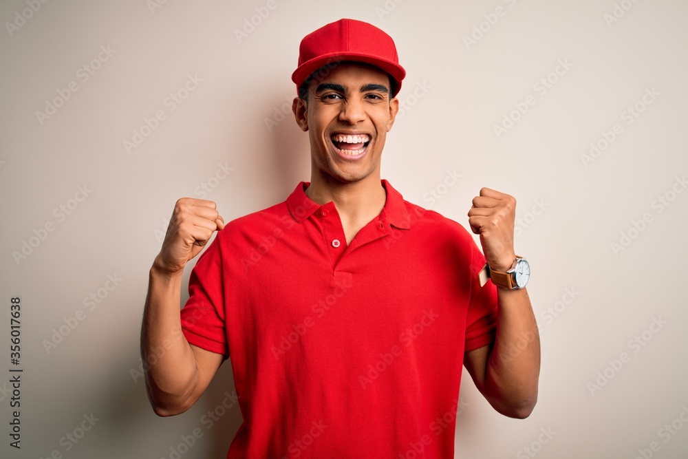 Young handsome african american man wearing casual polo and cap over red background celebrating surprised and amazed for success with arms raised and open eyes. Winner concept.