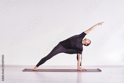 Man in yoga asana. Home lockdown studio. One person. Gym fitness. Morning meditating exercise. sport workout. Caucasian male relaxation. Balance energy mudra. Black. Horizontal. parsvakonasana photo