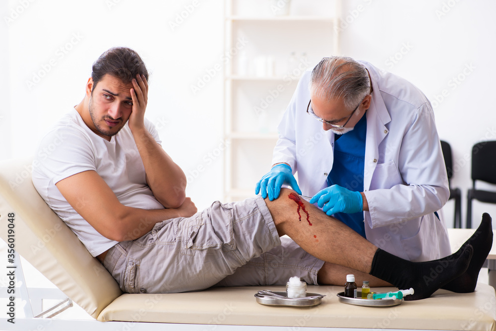 Fototapeta premium Leg injured man visiting old doctor in first aid concept