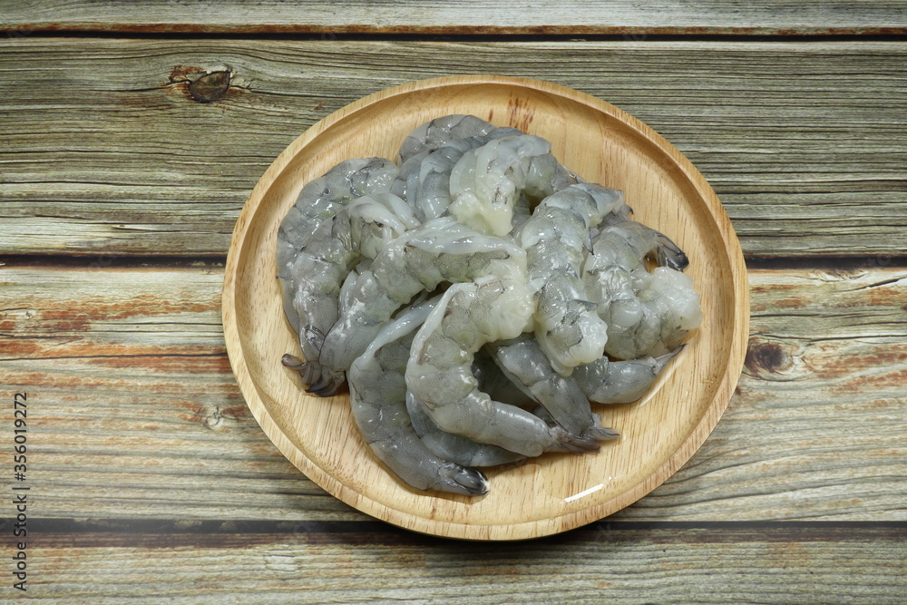 Fototapeta premium Fresh peeled shrimp on the wooden plate. Preparation raw material in the kitchen. Famous seafood ingredients in Asia. 