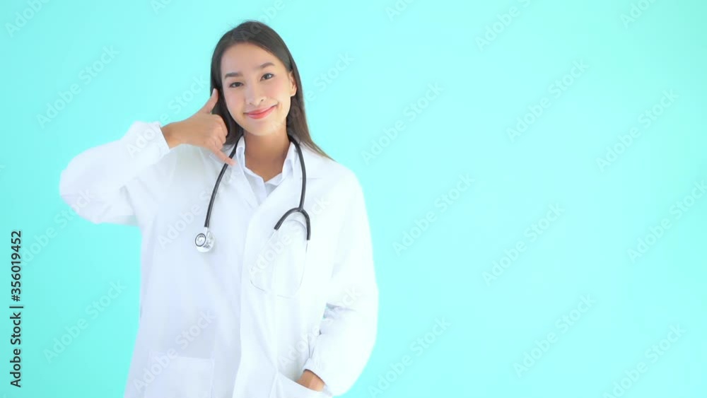 A young Asian woman in a white lab coat and a stethoscope around her neck uses her hand to signal to call me. Copy space A young Asian woman in a white lab coat and a stethoscope around her neck uses her hand to signal to call me. Copy space