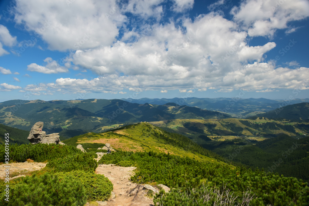 Landscape of mountainous rocky terrain with a trail on a background of blue sky Landscape of mountainous rocky terrain with a trail on a background of blue sky