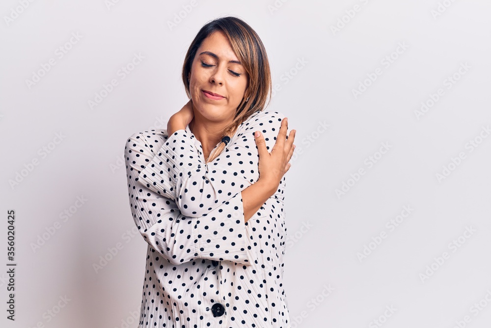 Young beautiful woman wearing casual dress hugging oneself happy and positive, smiling confident. self love and self care Young beautiful woman wearing casual dress hugging oneself happy and positive, smiling confident. self love and self care
