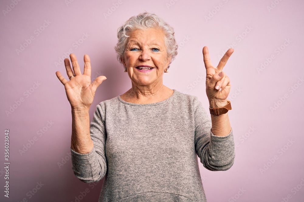 Senior beautiful woman wearing casual t-shirt standing over isolated pink background showing and pointing up with fingers number seven while smiling confident and happy. Senior beautiful woman wearing casual t-shirt standing over isolated pink background showing and pointing up with fingers number seven while smiling confident and happy.