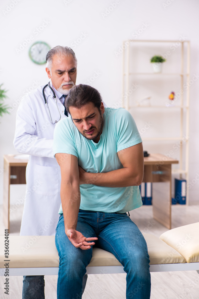 Obraz premium Injured young man visiting old doctor