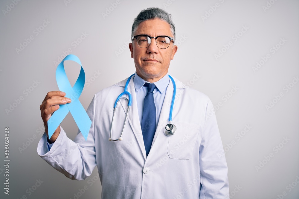 Middle age handsome grey-haired doctor man wearing coat holding blue cancer ribbon with a confident expression on smart face thinking serious Middle age handsome grey-haired doctor man wearing coat holding blue cancer ribbon with a confident expression on smart face thinking serious
