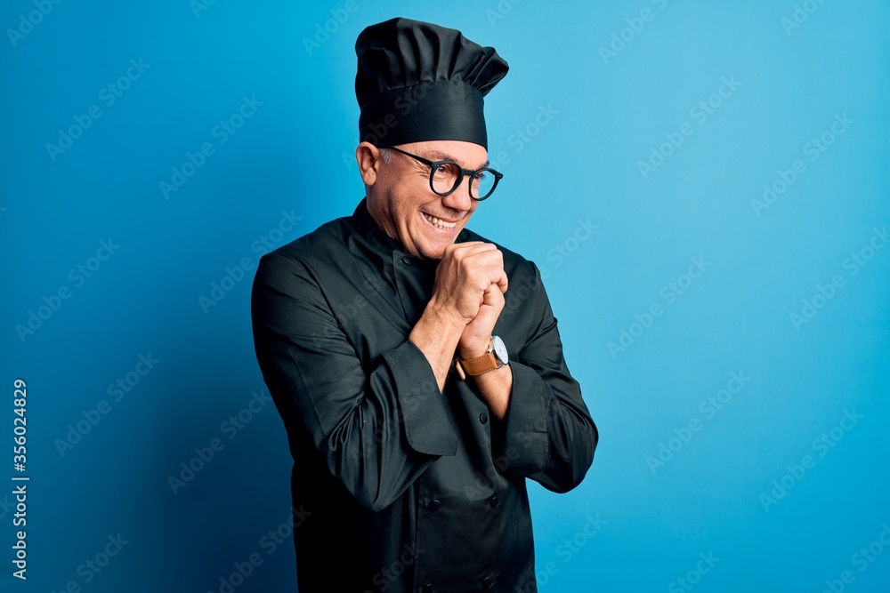 Middle age handsome grey-haired chef man wearing cooker uniform and hat laughing nervous and excited with hands on chin looking to the side Middle age handsome grey-haired chef man wearing cooker uniform and hat laughing nervous and excited with hands on chin looking to the side