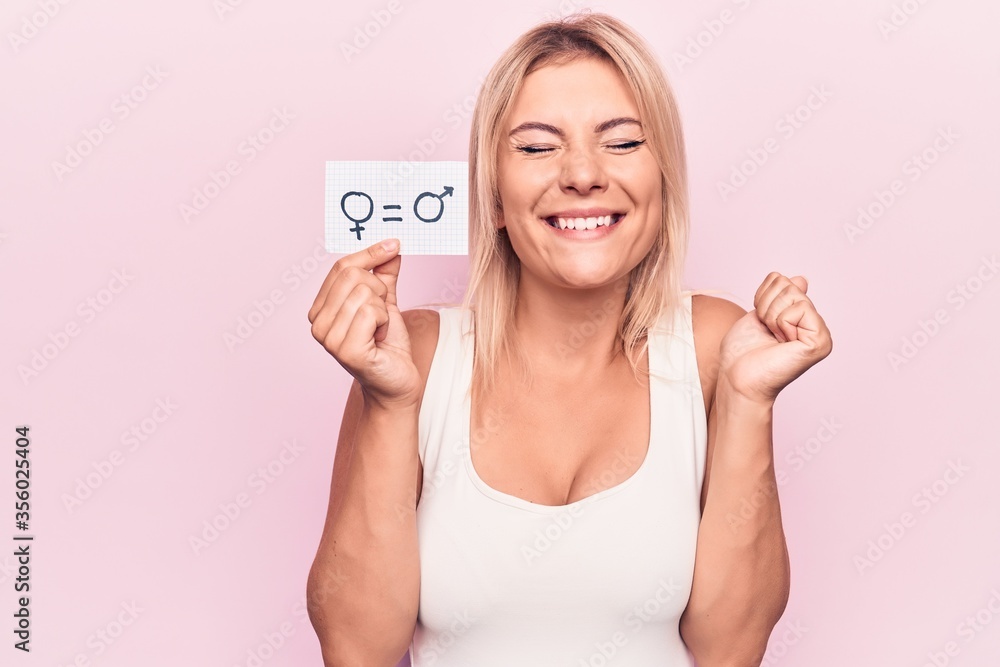 Young blonde woman asking for sex discrimination holding paper with gender equality message screaming proud, celebrating victory and success very excited with raised arm Young blonde woman asking for sex discrimination holding paper with gender equality message screaming proud, celebrating victory and success very excited with raised arm