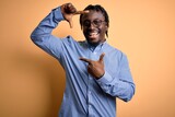 Young handsome african american man wearing shirt and glasses over yellow background smiling making frame with hands and fingers with happy face. Creativity and photography concept.