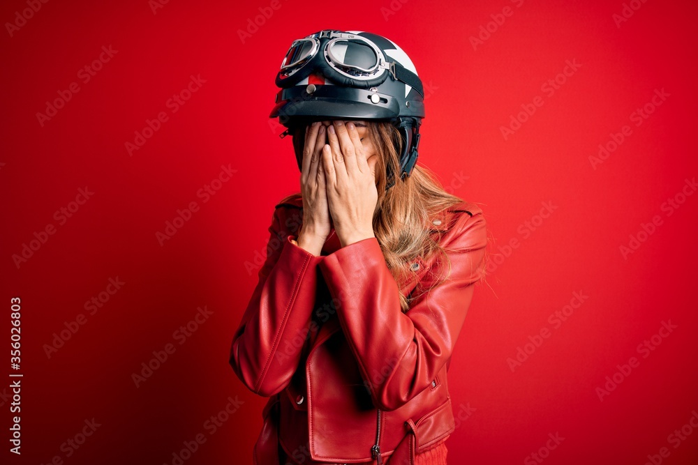Young beautiful brunette motrocyclist woman wearing moto helmet over red background with sad expression covering face with hands while crying. Depression concept. Young beautiful brunette motrocyclist woman wearing moto helmet over red background with sad expression covering face with hands while crying. Depression concept.