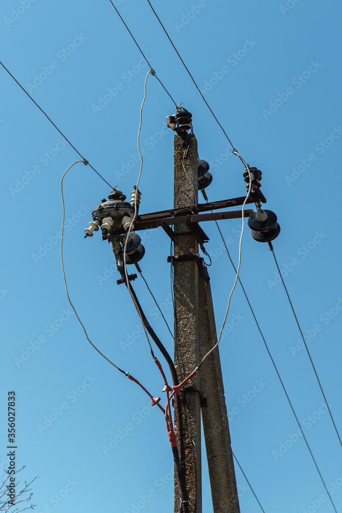 Power line post with electricity cables against a clear sky with white clouds. Power line post with electricity cables against a clear sky with white clouds.