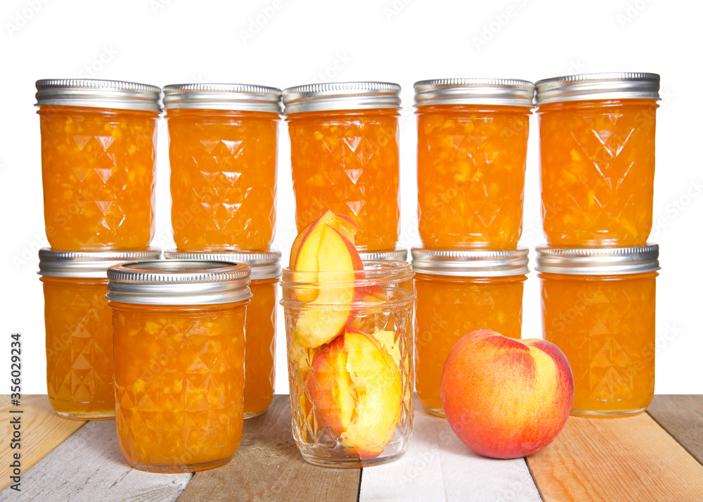Fresh sliced peaches in an open mason jar with whole peach on table