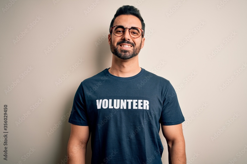 Handsome man with beard wearing t-shirt with volunteer message over white background with a happy and cool smile on face. Lucky person. Handsome man with beard wearing t-shirt with volunteer message over white background with a happy and cool smile on face. Lucky person.