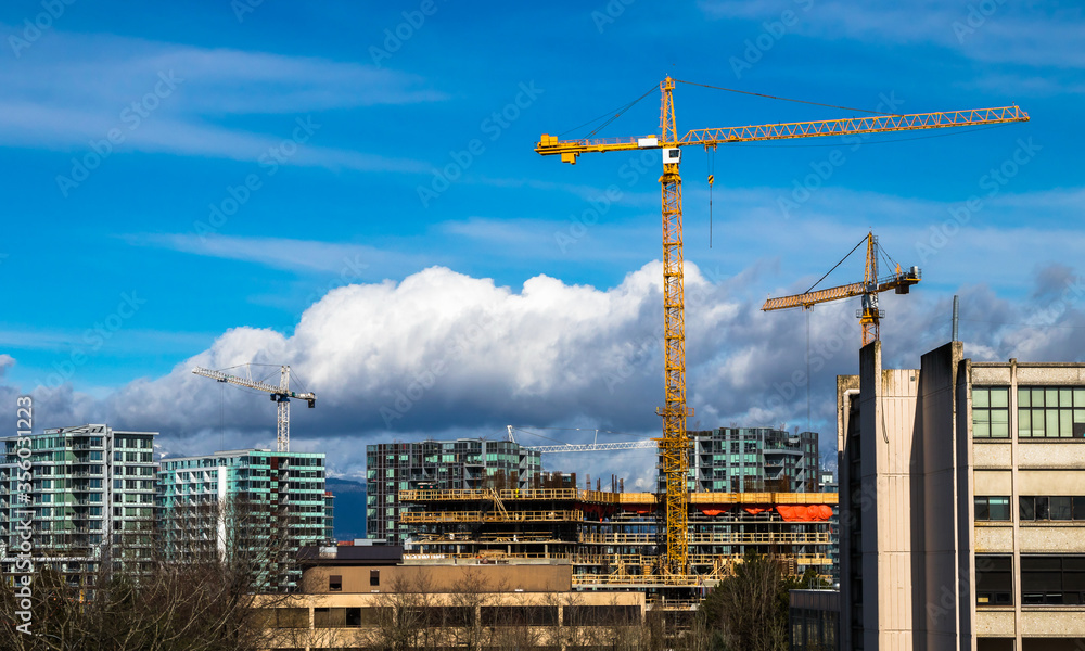 Construction of high-rise buildings in Richmond city, industrial construction site, construction equipment, several construction cranes on the background of a blue cloudy sky Construction of high-rise buildings in Richmond city, industrial construction site, construction equipment, several construction cranes on the background of a blue cloudy sky