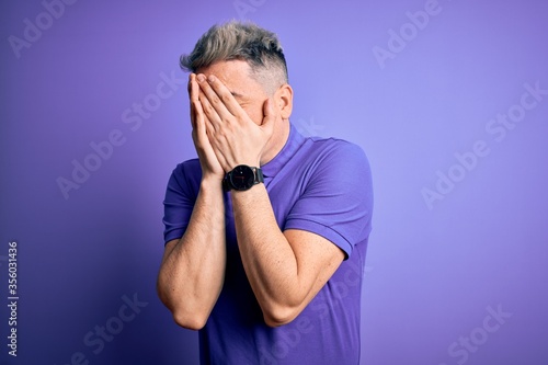 Young handsome modern man wearing casual purple t-shirt over isolated background with sad expression covering face with hands while crying. Depression concept. © Krakenimages.com