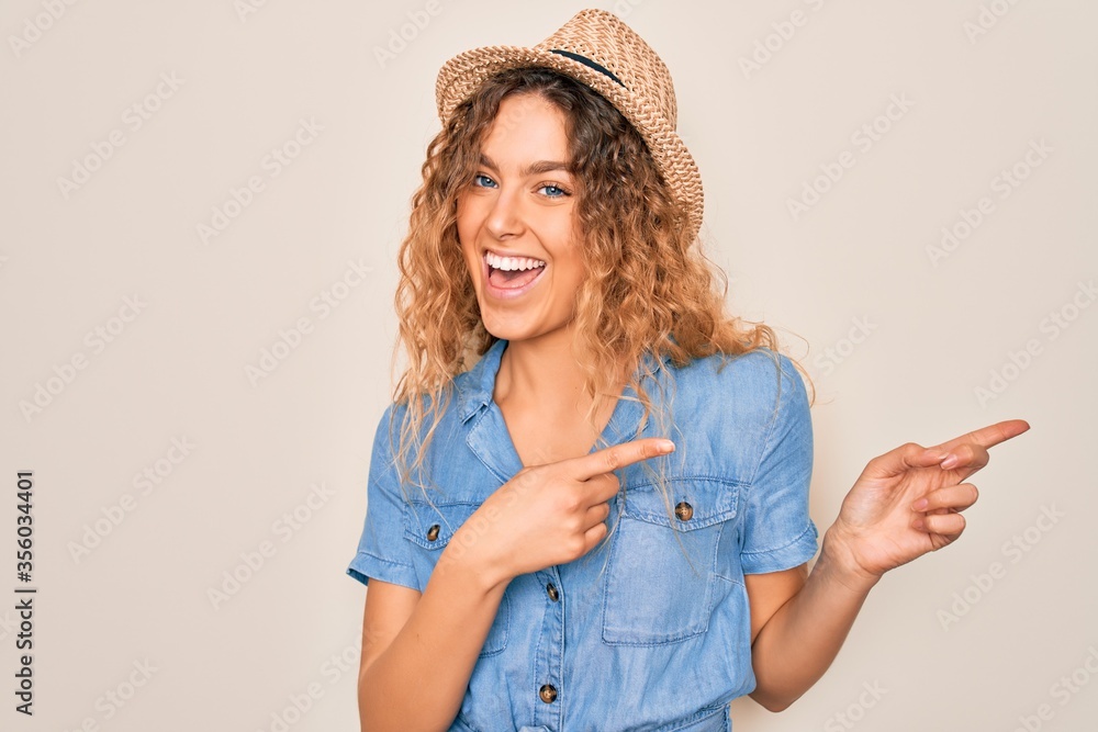 Young beautiful woman with blue eyes wearing casual denim dress and summer hat smiling and looking at the camera pointing with two hands and fingers to the side. - obrazy, fototapety, plakaty 