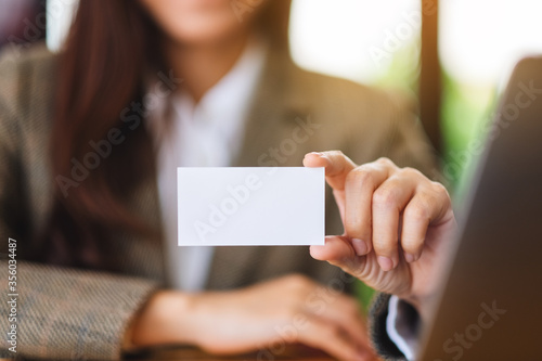 A businesswoman holding and showing a blank business cards in office