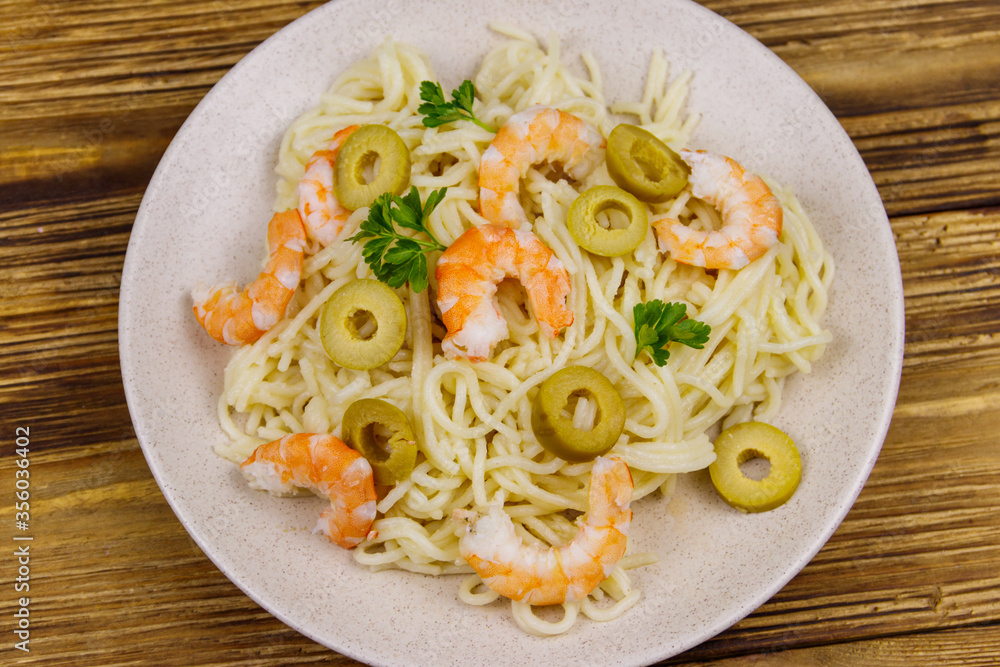 Spaghetti pasta with prawns, green olives and parsley on wooden table. Top view Spaghetti pasta with prawns, green olives and parsley on wooden table. Top view