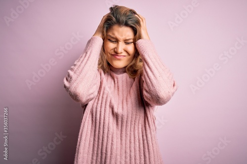 Young beautiful blonde woman wearing casual pink sweater over isolated background suffering from headache desperate and stressed because pain and migraine. Hands on head. © Krakenimages.com