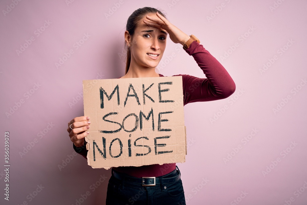 Beautiful activist woman holding banner with make some noise message over pink background stressed with hand on head, shocked with shame and surprise face, angry and frustrated. Fear and upset Beautiful activist woman holding banner with make some noise message over pink background stressed with hand on head, shocked with shame and surprise face, angry and frustrated. Fear and upset