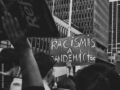 Protestors chanting passionately during the BLM protest in Sydney 2020. Large signs reads 'Racism is a pandemic too'. Taken from deep within the crowd.