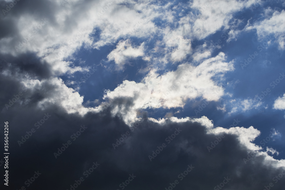 Overcast blue sky with dark cumulus clouds on a sunny day
