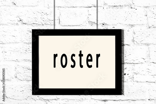 Fotografia Black frame hanging on white brick wall with inscription roster