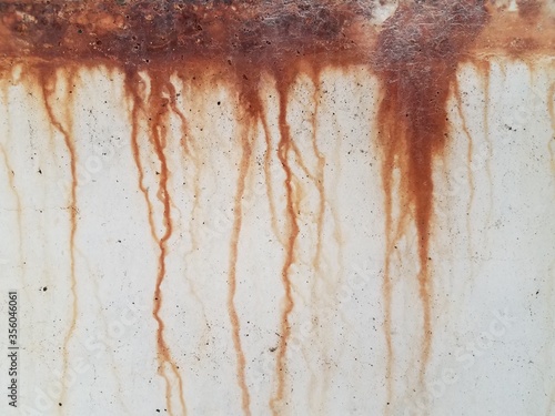 grey cement wall with red rust dripping down