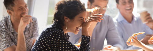 Laughing indian businesswoman in friends company eating pizza enjoy lunch together with colleagues, team building corporate party, friendship concept. Horizontal photo banner for website header design photo